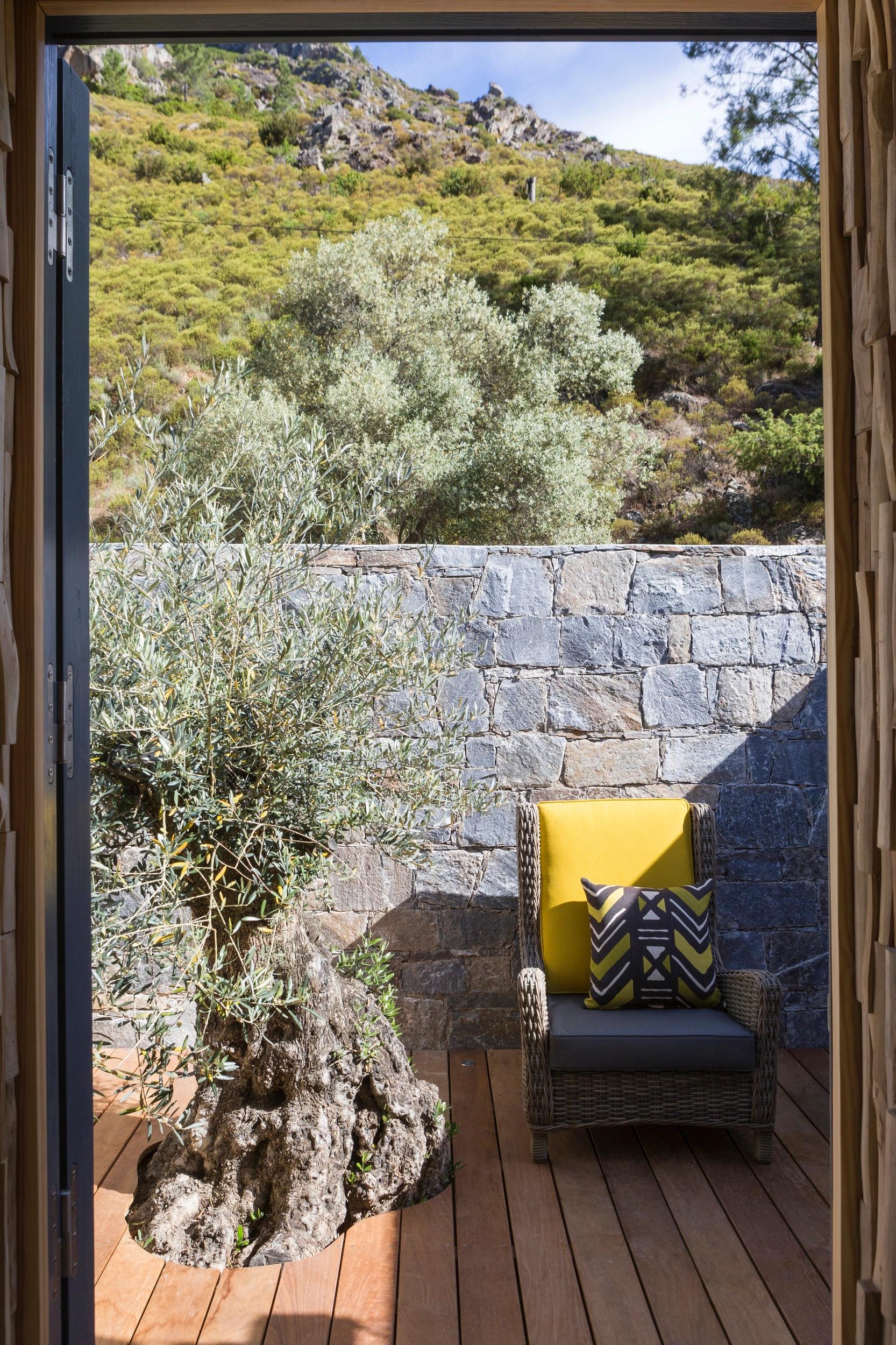 Terrasse privée de la suite L’Alba avec mobilier en bois et vue sur la rivière