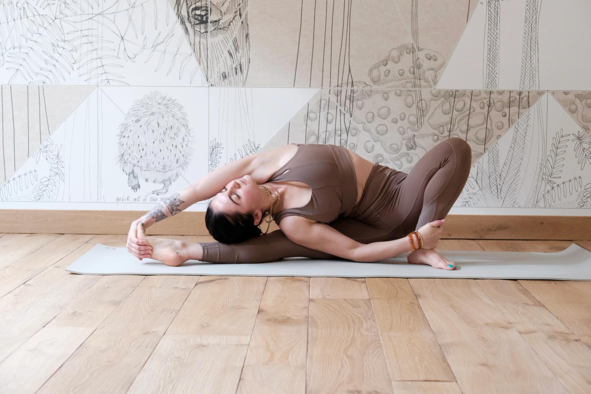 Posture de yoga sur tapis posé au sol dans une salle au design épuré